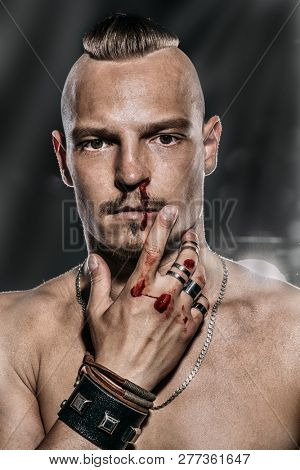 Fight club, MMA. Portrait of a bad guy fighter with a face in the blood, demonstrating his muscles and strength. Rocker, punk. 