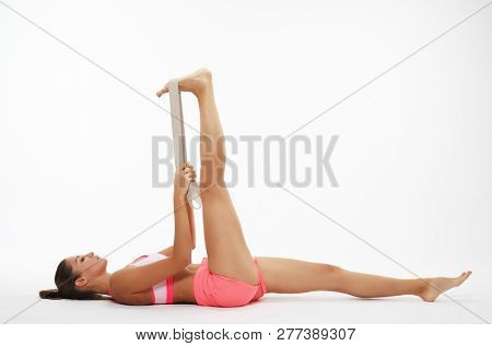 Motivation, fitness and people concept: Sporty woman  doing a exersize  with resistance band. Photo of young woman in fashionable sportswear on white background.  