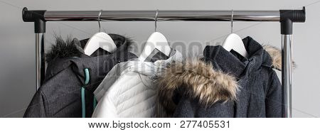 Hanger Stand With Warm Jackets. Winter Jackets With Fur Collar Hang On White Wooden Hangers. Collect