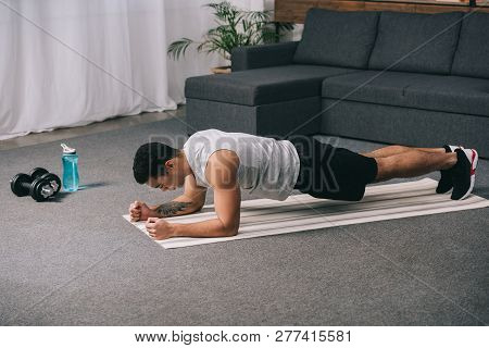 Bi-racial Athlete Doing Plank Exercise On  Fitness Mat