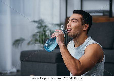 Cheerful Bi-racial Man Drinking Water From Sport Bottle