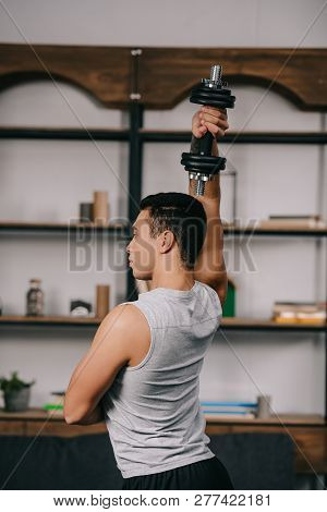 Strong Bi-racial Man Exercising With Dumbbell In Living Room
