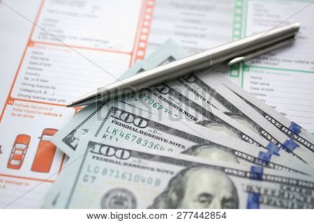 The Silver Pen With Dollar Banknotes Is On The International Euro-protocol Form For Filling And Inde