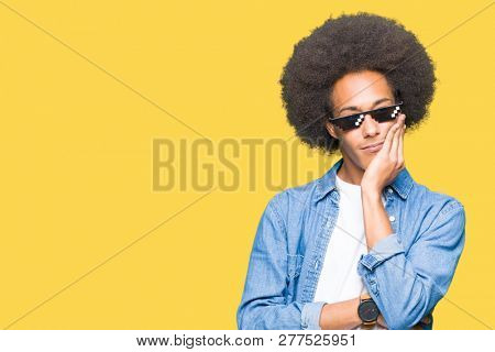 Young african american man with afro hair wearing thug life glasses thinking looking tired and bored with depression problems with crossed arms.