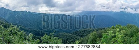 Panoramic View Of A Mountain Range Covered With Forest In Thick Clouds. The Main Caucasian Ridge. Ch
