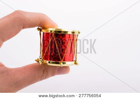 Hand Holding A Small Drum On A White Background