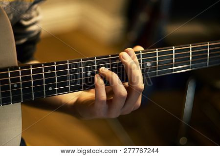 The Guitarist Holds A Chord On The Guitar Fretboard