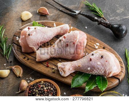 Chicken legs with spices and salt  ready for cooking on cutting board.