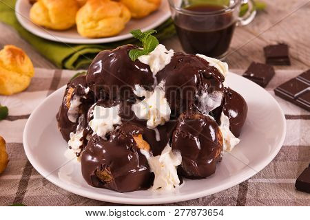 Chocolate Profiteroles With Whipped Cream On White Dish.