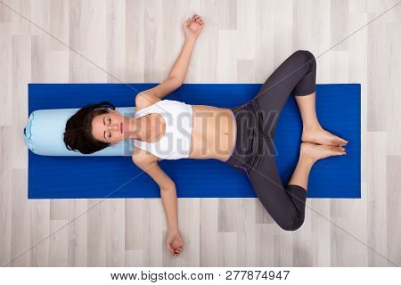 Young Woman Practicing Yoga On Bolster At Home