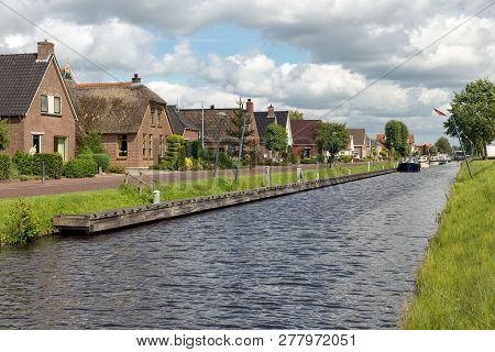 Dutch Village Appelscha In Friesland With Houses Along A Canal And A Beautiful Cloudy Sky