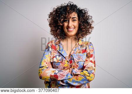 Young beautiful curly arab woman wearing floral colorful shirt standing over white background happy face smiling with crossed arms looking at the camera. Positive person.