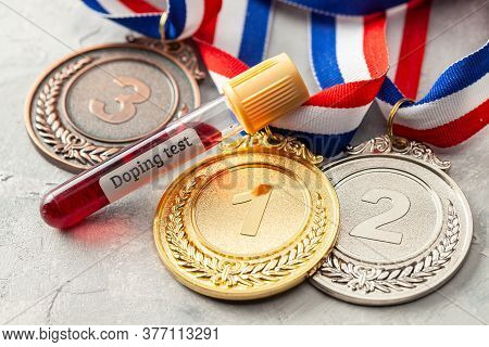 Doping Test. Gold, Silver And Bronze Medal And Test Tube With Blood On A Gray Background