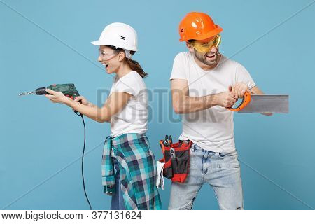 Cheerful Couple Woman Man In Protective Helmet Hardhat Hold Electric Drill Saw Isolated On Blue Back