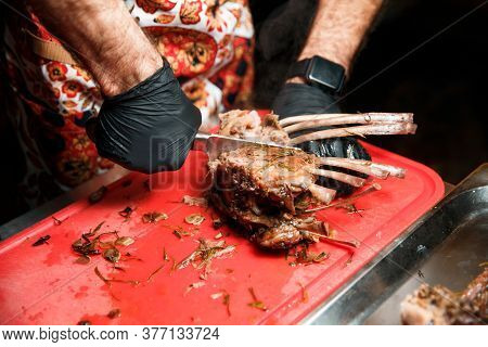 Chev Cuts Juicy Cooked Meat, Separating The Meat From The Bone With A Knife.