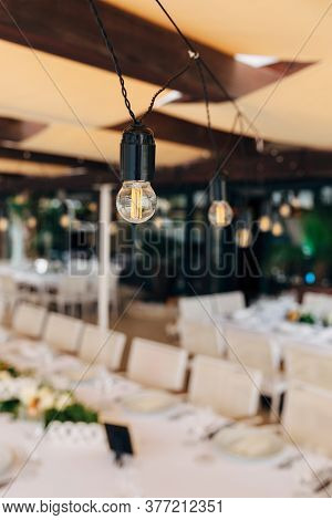 Garlands Of Led Lamps Over A Banquet Table For A Wedding Dinner.