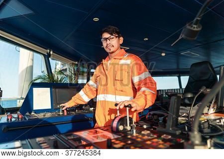 Filipino Deck Officer On Bridge Of Vessel Or Ship. He Is Speaking On Gmdss Vhf Radio
