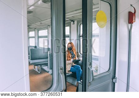 Girl In A Mask, With A Smartphone In Her Hands In A Train Car.