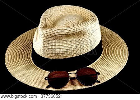 Straw Panama Hat And Sunglasses Isolated Against A Black Background