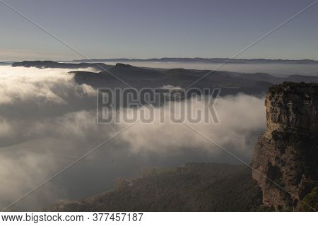 Landscape Showing A Cliff Partially Covered By A Layer Of Fog Under A Blue Sky In Tavertet Town In C