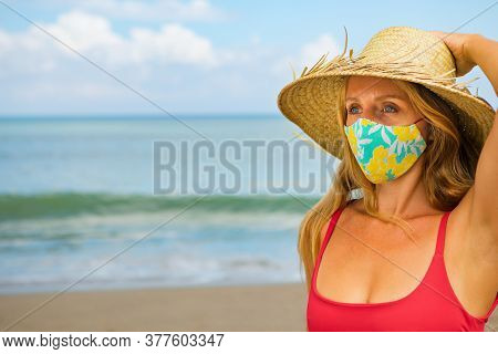 Funny Portrait Of Young Woman In Straw Hat On Tropical Sea Beach. New Rules To Wear Cloth Face Cover