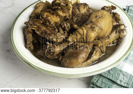 A Serving Of Filipino-style Chicken Adobo Dish In A Bowl With Green Napkin Set On A Marble Tabletop.