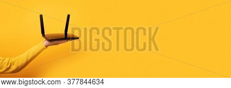 Black Wifi Router On Female Hand Over Yellow Background, Panoramic Mock-up Image