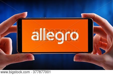 Hands Holding Smartphone Displaying Logo Of Allegro