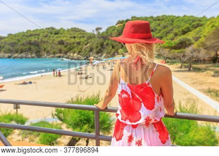 Back Side Of Elegant Lifestyle Woman With Red Wide Hat On Roof Top At Fetovaia Beach. Caucasian Tour