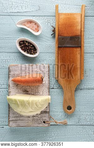 Wooden Cabbage Grater, Piece Of Cabbage, Carrot, Assorted Pepper And Himalayan Salt On Cutting Board