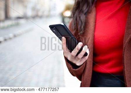 Mobile Phone In A Woman's Hand. Cell Phone In Hand. Using Cell Phone On The Street.
