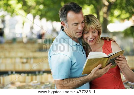 Lyckliga par läsa en guidebok utomhus