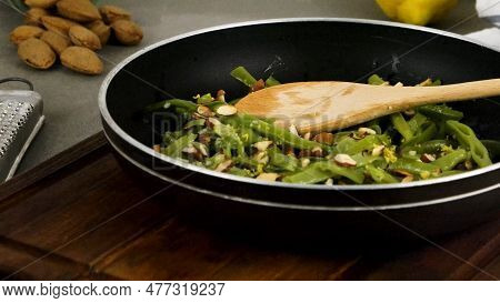 Green Beans With Roasted Almonds On Fry Pan On Kitchen Countertop. Slide From Right.