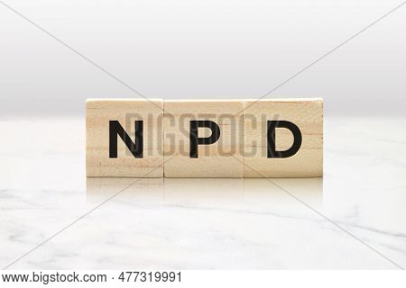 Three Wooden Tiles Spelling Npd Against A Classy White Marble Background.