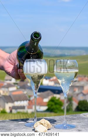 Pouring Of Grand Cru Sparkling White Wine With Bubbles Champagne With View On Houses And Vineyards G