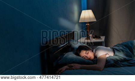 Young Woman Sleeping In Soft Bed In Late At Night. Lying Cozily In Bed, Hugging A Pillow. Girl Sound