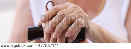 Close-up Of Female Old Hands Holding Wooden Walking Cane. Elderly Woman Using Supporting Stick. Old 