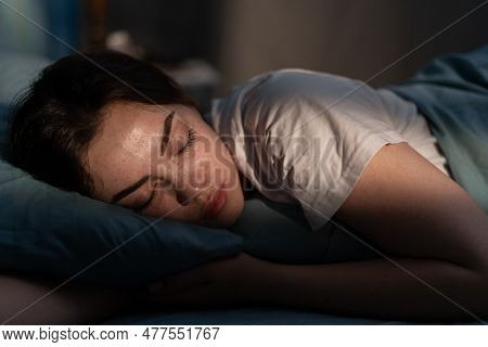 Portrait Of Beautiful Young Woman Sleeping Cozily On A Bed In Her Bedroom At Night.