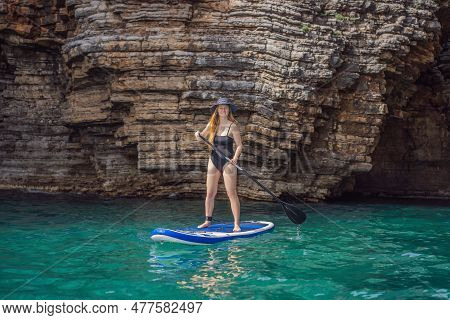 Young Women Having Fun Stand Up Paddling In Blue Water Seaamong The Rocks In Montenegro. Sup
