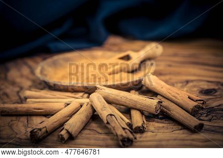 Dried Cinnamon Sticks And Powder On Olive Wood