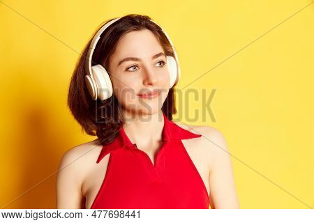 Portrait Of Beautiful, Attractive Young Brunette Girl Listening To Music In Headphones Against Yello