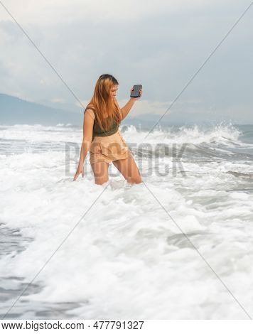 Beautiful Young Filipina Woman,playfully Paddling In The Shallow Waves Of The Long Sandy Beach At Ib