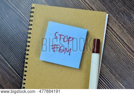 Concept Of Stop Fgm Write On Sticky Notes Isolated On Wooden Table.