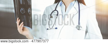 Professional Young Woman Doctor Is Looking At Her Patients Roentgenogram In Sunny Clinic. Medicine C
