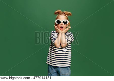 Portrait Of Emotiona, Beautufl Little Girl, Childin Striped Shirt And Sunglasses Posing Against Gree