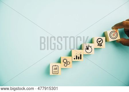 Hand Arranging Wood Block Stacking To Represent The Business Strategy And Action Plan On A Blue Back