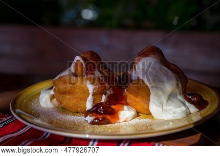 Papanasi - A Traditional Romanian Dessert. The Cake Is Made From Three Donuts Covered In Sour Cream 