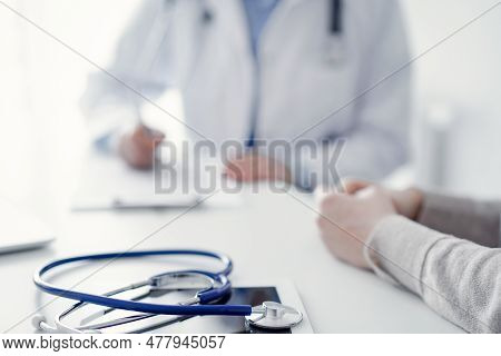 Stethoscope Lying On The Tablet Computer In Front Of A Doctor And Patient At The Background . Medici