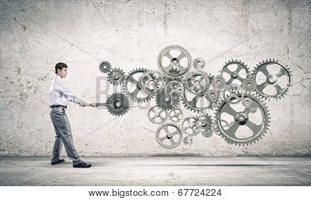 Young businessman fixing gears mechanism with wrench