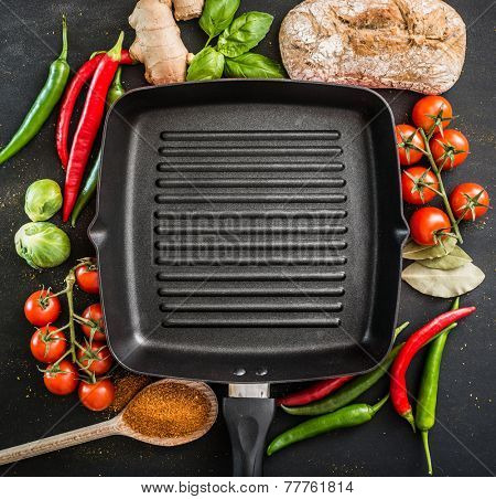 Cast iron griddle pan on black background with vegetables